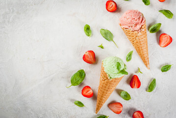 Summer fresh desserts. Green basil and red strawberry ice cream in a cone. On a white stone table with basil leaves and fresh strawberries around. On a white stone table. Top view copy space