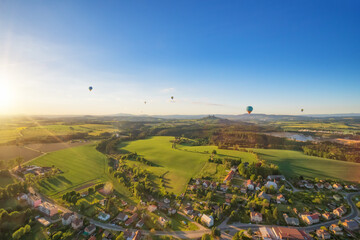 Group of hot air balloons flying above rural countryside
