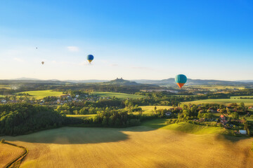 Naklejka premium Group of hot air balloons flying above rural countryside
