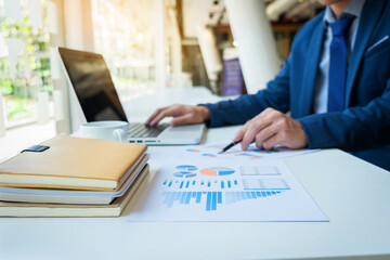 Business man working at office with laptop and documents on his desk. Analyze plans, papers, hands keyboard, business concept