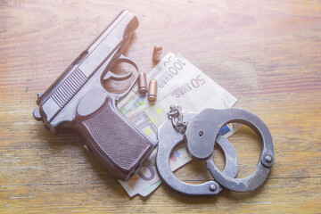 Obraz premium Gun, money and handcuffs on the wooden table. Crime concept