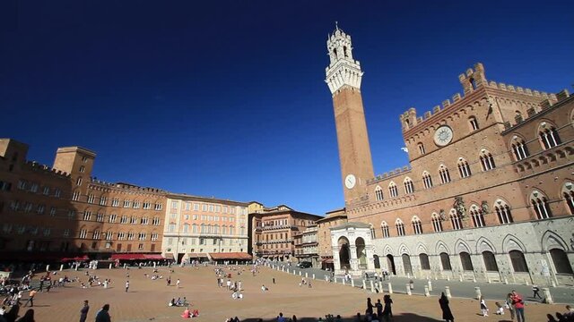 Siena, January 2017: Tourists in Campo Square with Mangia Tower in the background and Christmas decorations, on January 2017 in Siena, Tuscany, Italy