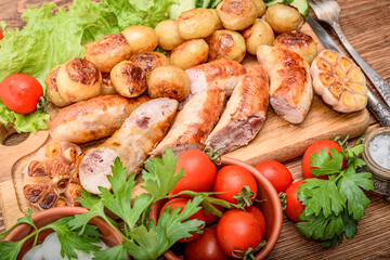 Grilled sausages and vegetables on the wooden board.