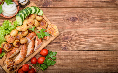 Grilled sausages and vegetables on the wooden board.