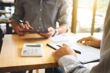 Two business colleague meeting to discussing the new project business strategy plan with using digital tablet and calculator. Briefing, brainstorming, consulting. blurred back ground