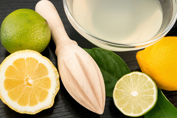 Healthy food and vitamins: a wooden juicer and fresh lemon and lime with leaves and freshly...