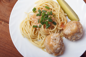 Spaghetti pasta with meatballs with green onion on wooden background