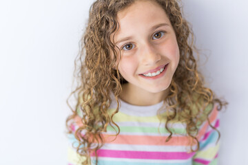 Portrait of 9 years old girl with curly hair, isolated on gray