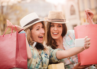 Shopping time. Beautiful smiling girls enjoying in shopping, having fun together. Consumerism, fashion, lifestyle concept