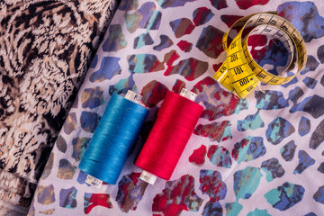Red and blue thread spool on textile background.