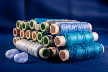 Still life of blue thread spool on dark blue background.