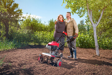 Happy couple of a family of farmers on their garden rejoice on a sunny day after plowing the land