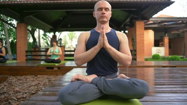 Man meditating in the lotus pose sitting on the green carpet slow motion