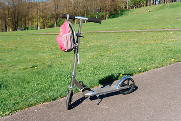 Obraz premium Scooter and backpack next to the green meadow.