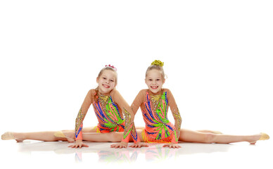 Two girls gymnast sitting on splits.
