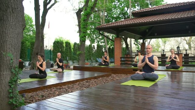 Group of people sitting in the lotus pose meditating slow motion