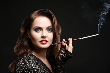 Beautiful woman smoking cigar on dark background