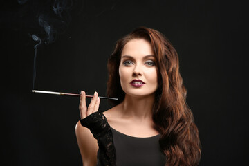 Beautiful woman smoking cigar on dark background