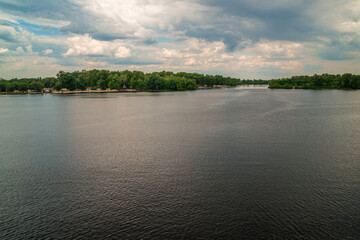 Natural background, lake or river, forest and sky with clouds, on the whole frame. Horizontal frame