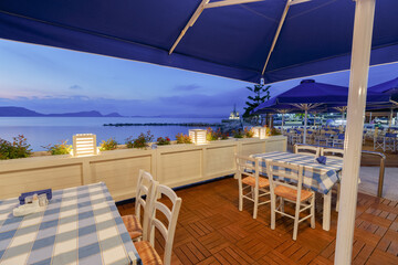 Cafe bar terrace, view at Mediterranean sea. Evening scenery, Ormos Navarinou harbor, Pilos town, Greece.