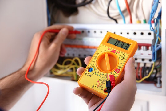 Young electrician measuring voltage in distribution board