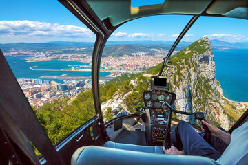 Aerial view of top of Gibraltar Rock. Gibraltar is a territory of South West Europe which is part of the United Kingdom. Helicopter cockpit with pilot arm and control console inside the cabin.