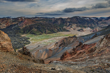 Wonderful icelandic landscape. grass land, lake, high multicolored mountains, and beautiful sky.