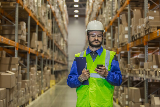 Warehouse Worker In Hard Hat Using Mobile Phone