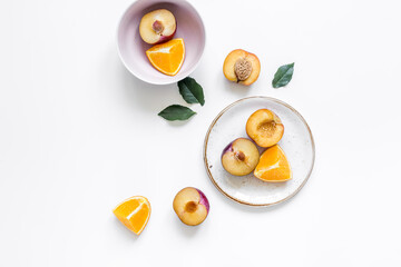 woman summer breackfast with orange and peach fruits on plates on white background flat lay