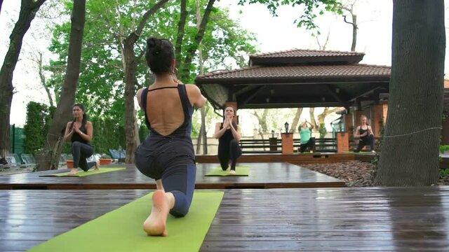 Group of people standing in the low lunge posture slow motion