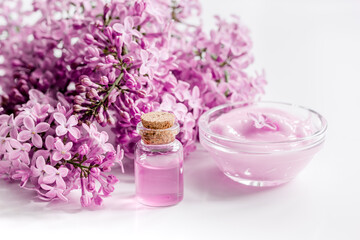 Fototapeta na wymiar spa cosmetic set with lilac flowers white desk background