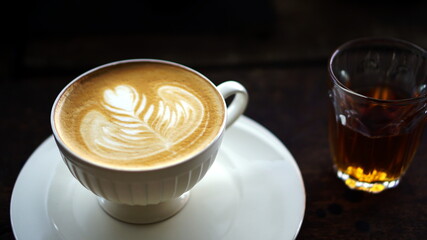 Cappuccino coffee with art of milk. A cup of latte, cappuccino or espresso coffee with milk. Latte art by milk on top with flowers.