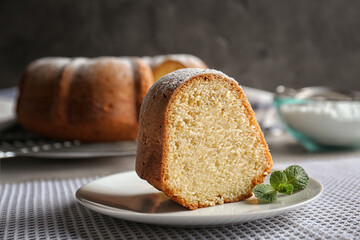 Saucer with slice of delicious yogurt cake on tablecloth