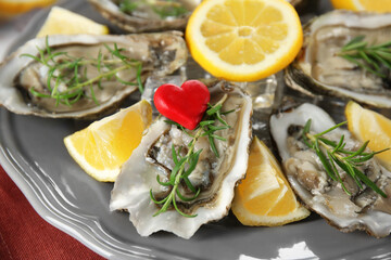 Tasty fresh oysters with sliced lemon and rosemary on plate. Aphrodisiac food for increasing sexual...