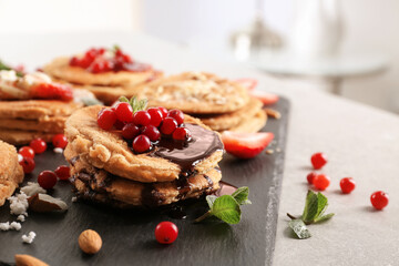Stack of delicious coconut pancakes with sweet sauce, berries and mint on slate plate, close up