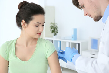 Fototapeta premium Young woman receiving injection from medical assistant in clinic