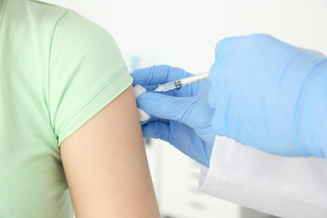 Fototapeta premium Young woman receiving injection from medical assistant in clinic, closeup