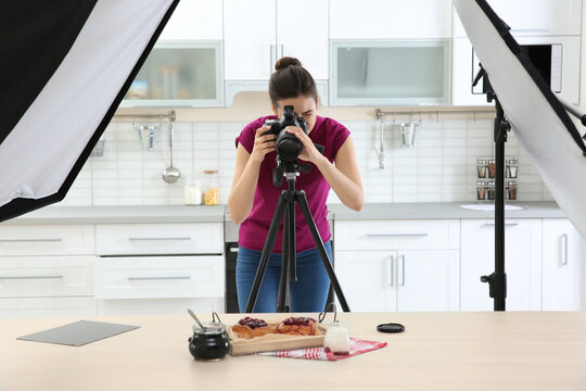 Young woman photographing food in photo studio