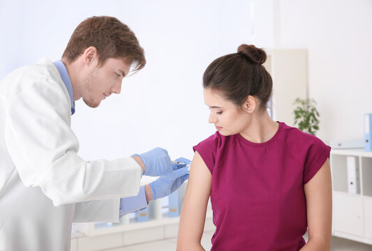 Young woman receiving injection from medical assistant in clinic