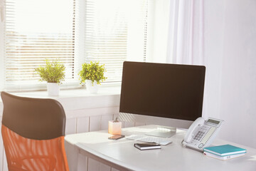 Modern comfortable workplace with computer and window blinds