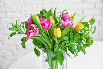 Glass vase with bouquet of beautiful tulips on blurred background