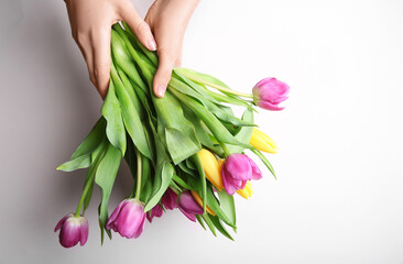 Fototapeta premium Woman holding beautiful tulips on light background