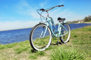 Fototapeta na wymiar Blue bicycle standing on grass near river