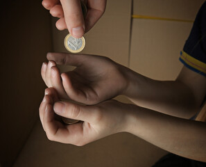 Female hand putting coin into hands of poor child, closeup