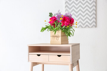 Gift box with beautiful floral composition of different fragrant flowers on table in light room