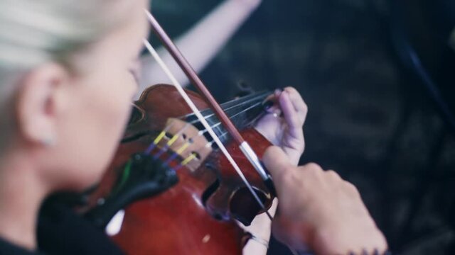 Female violinist playing violin. Close up of woman playing violin in orchestra concert. Violinist girl playing classical music instrument. Violin player playing music. Woman play violin
