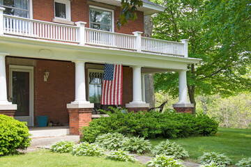 old brick home with American flag hanging on front porch