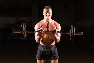 Fototapeta na wymiar Muscular man working out in gym doing exercises with barbell, strong male naked torso abs.