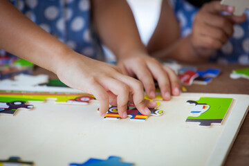 Child little girl hand trying to connect jigsaw puzzle piece to learn to find solution