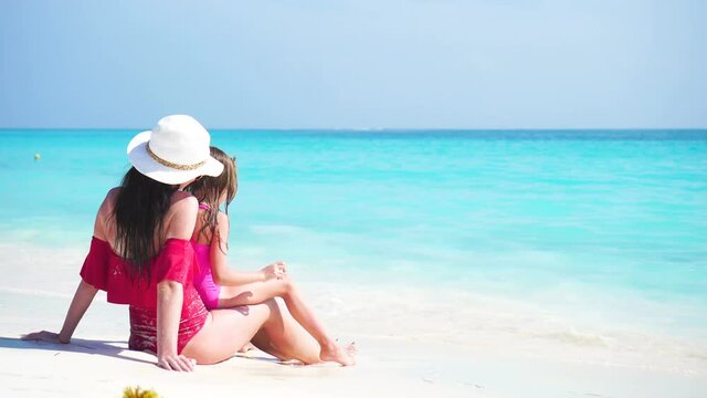 Little adorable girl and young mother at tropical beach enjoy their sea vacation